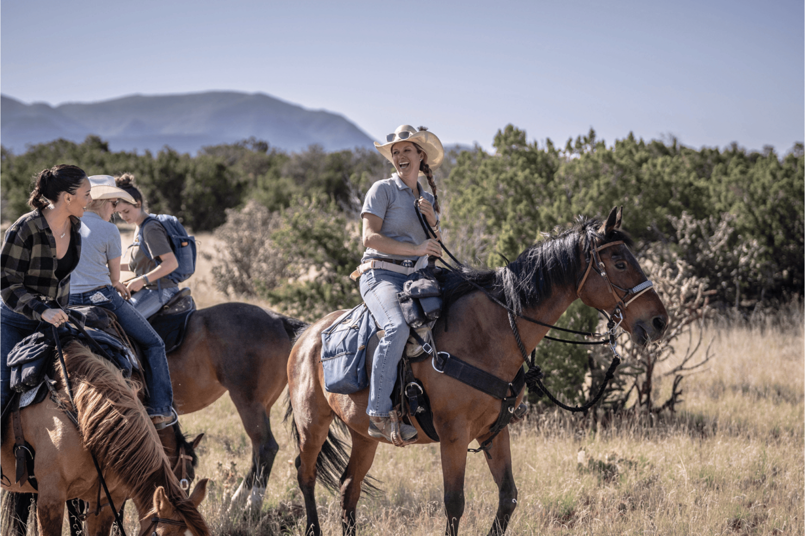 Justyn Vogel, owner of Enchantment Equitreks in Edgewood, makes riding a fun experience for all. Pictured here enjoying a laugh with a group of riders. (Photo by Roberto E. Rosales Photography)