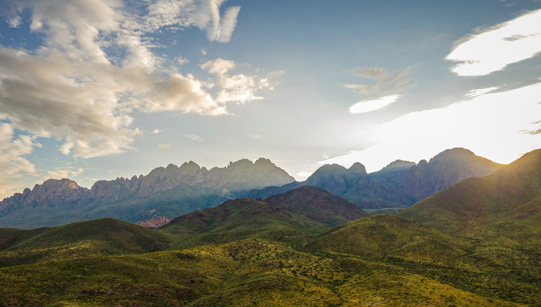 The Organ Mountains in the distance with green rolling hills in the foreground