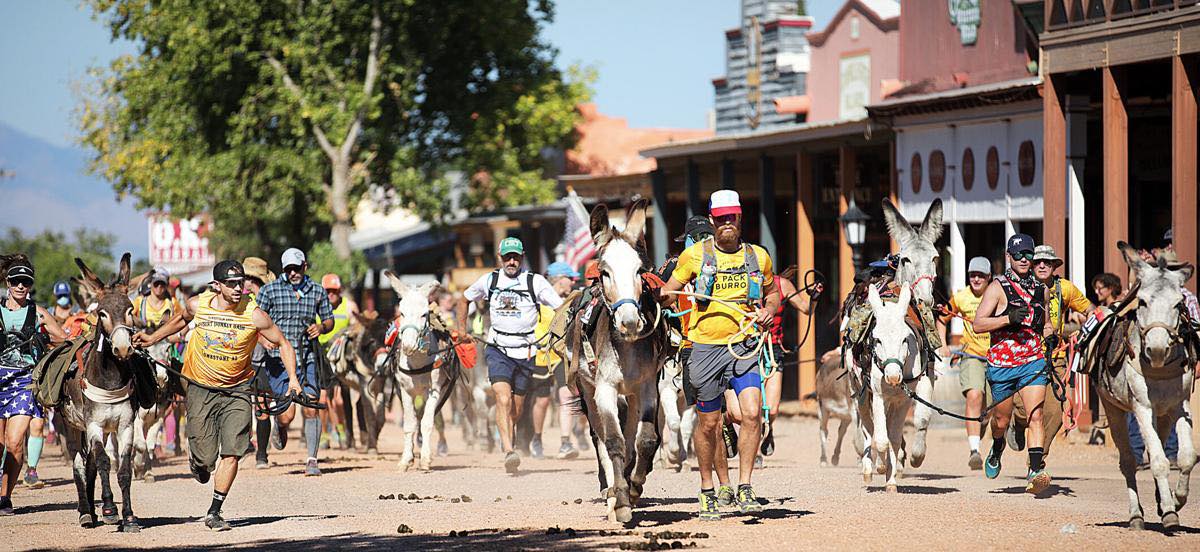 Runners leading burros as they race through a rural town in New Mexico
