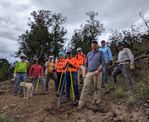 a group of trail workers pose with tools on a freshly built trail