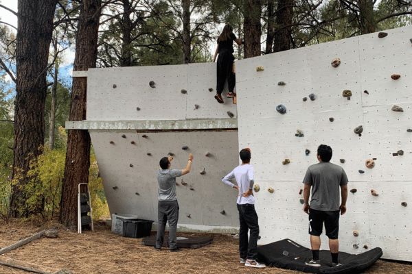 three young men looking at a homemade bouldering wall outside
