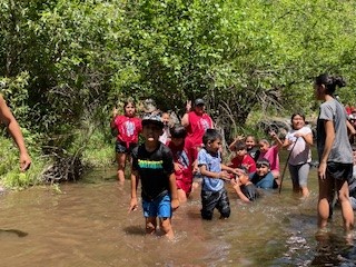 Group of kids walking in knee-deep water smiling
