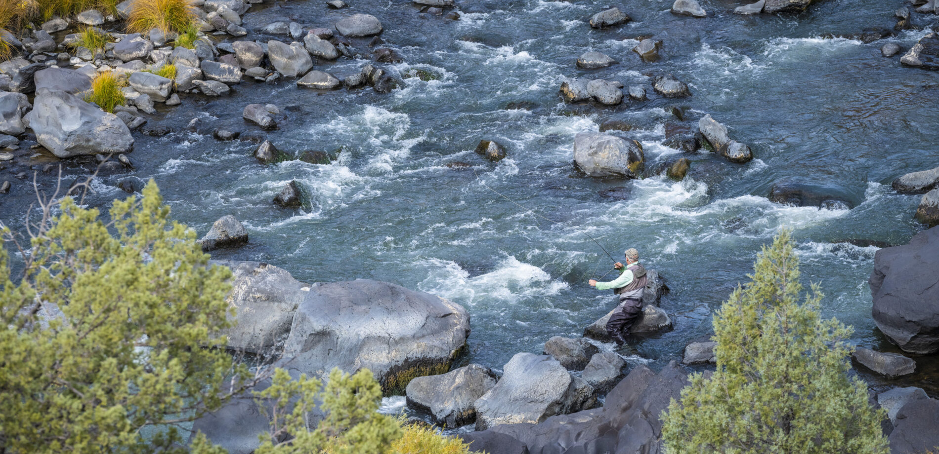aerial view of man fly fishing on a rocky river