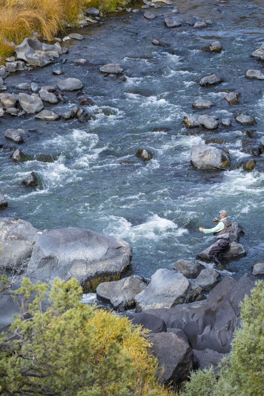 Mobile sized image of aerial view of man fly fishing on a rocky river
