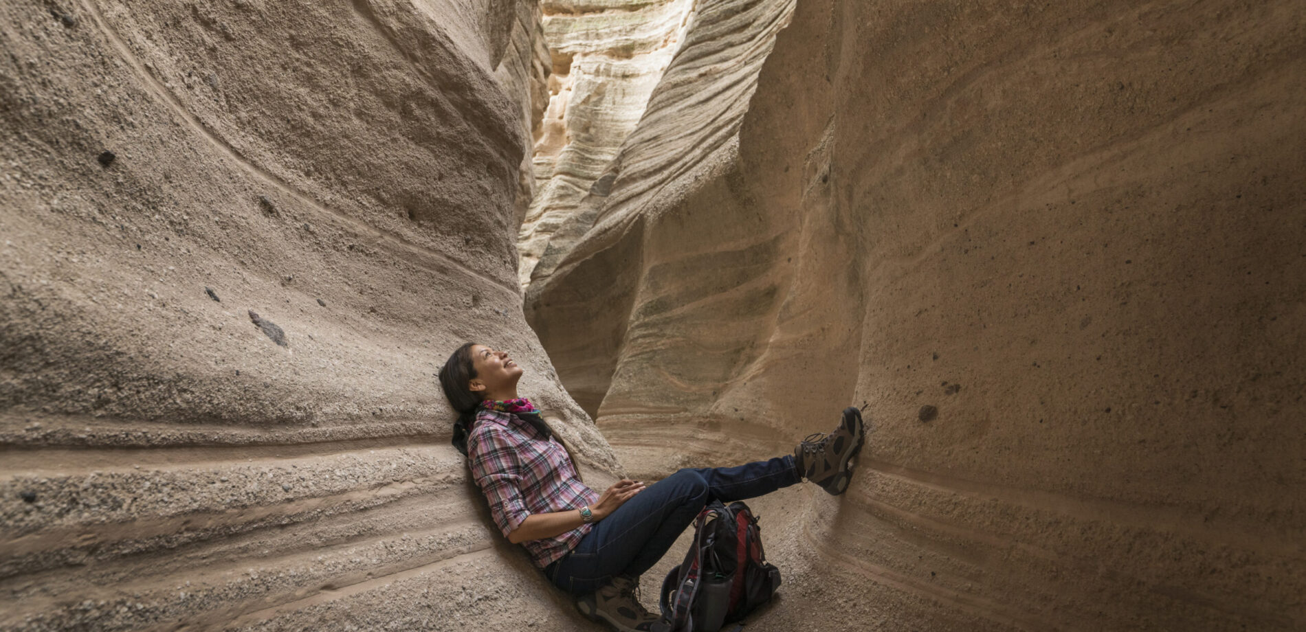 Woman sitting in a slot canyon looking up