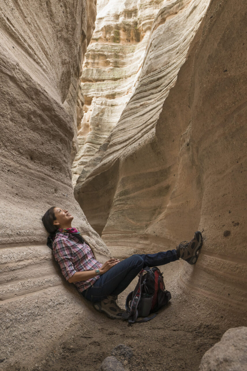 Mobile sized image of Woman sitting in a slot canyon looking up