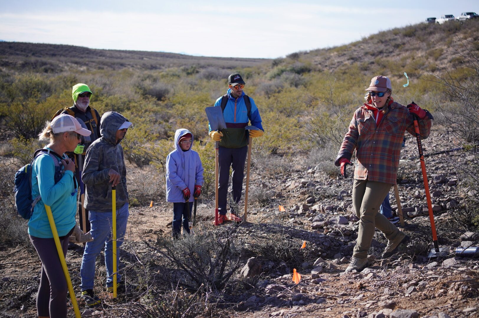 A trail worker explaining a technique to a group of volunteers on the trail