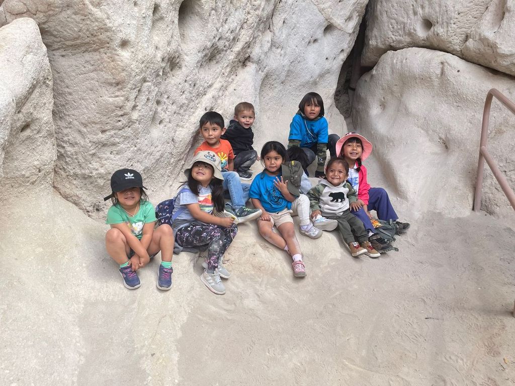 Group of young children smile while perched on a rock at Bandelier National Monument