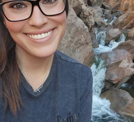 Woman smiling with a rocky waterfall behind her