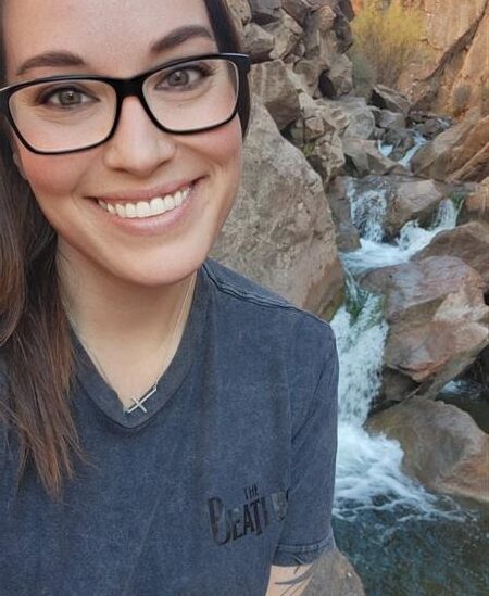 Woman smiling with a rocky waterfall behind her