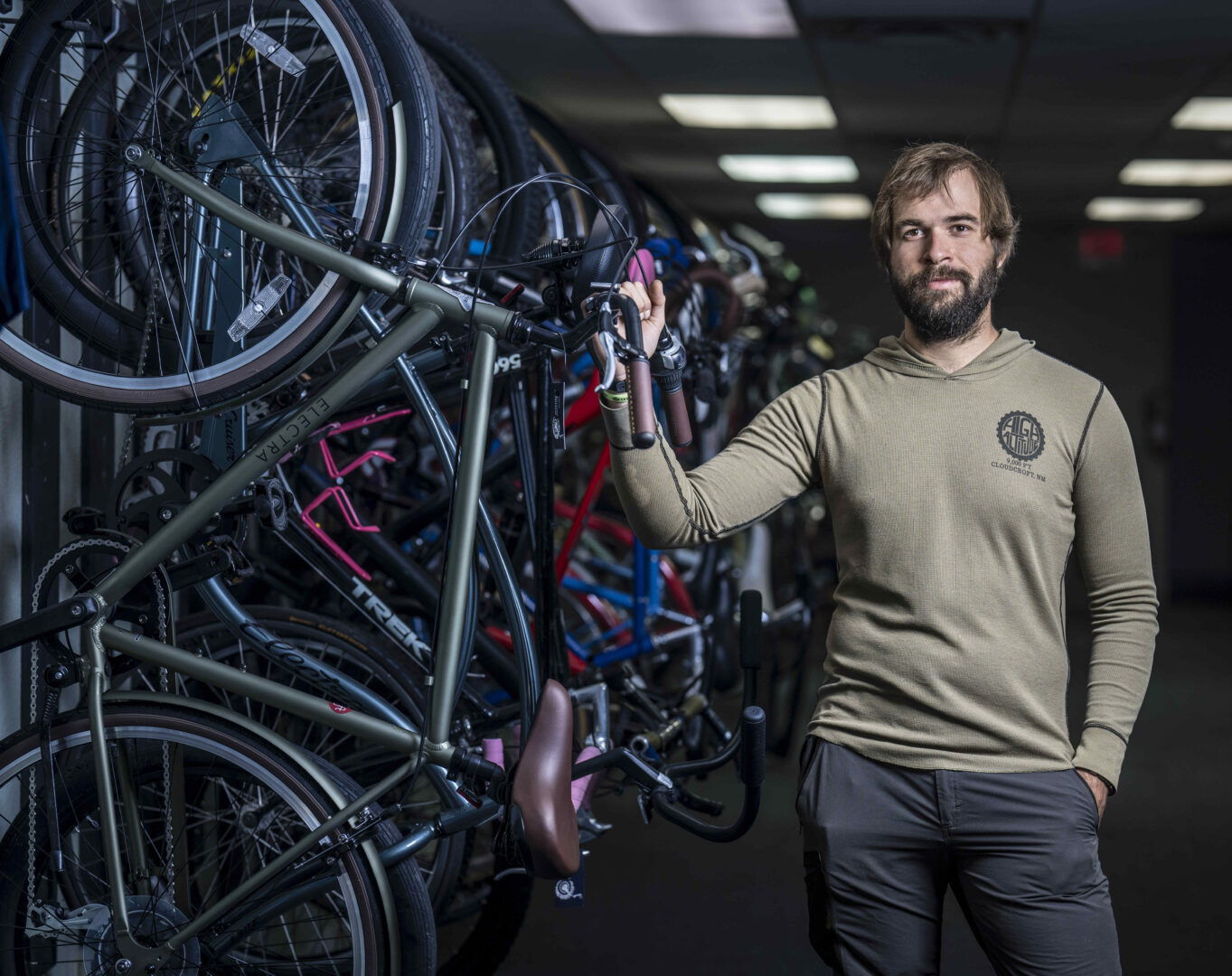 Man standing in a bike shop posing next to a wall of bikes