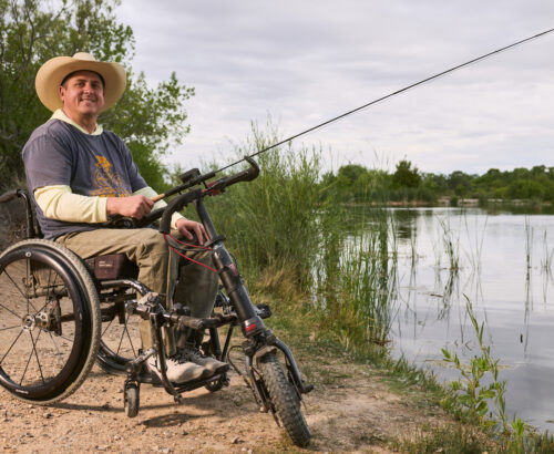 a man in a wheelchair fishing and smiling