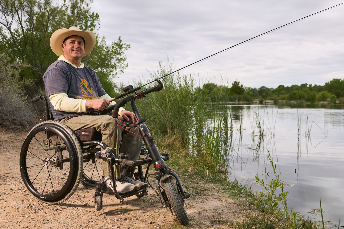 a man in a wheelchair fishing and smiling