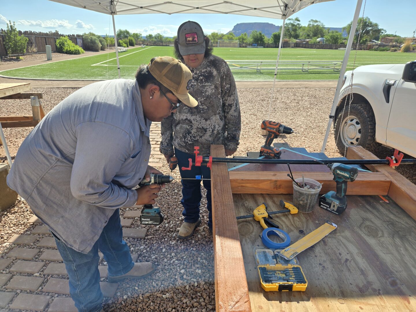A young man using a drill to construct a wooden sign