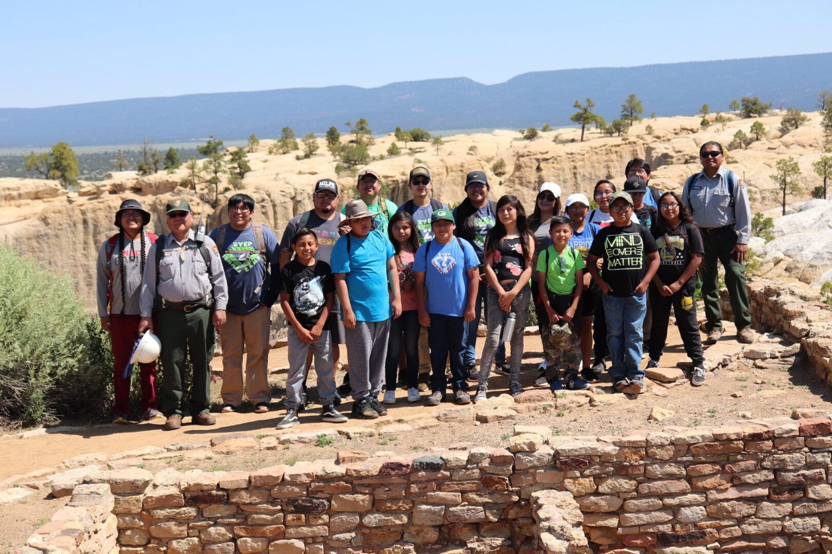 A group of children standing in front of a ruins site in the desert smiling