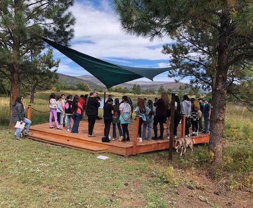 large group of kids standing outside on a wooden platform