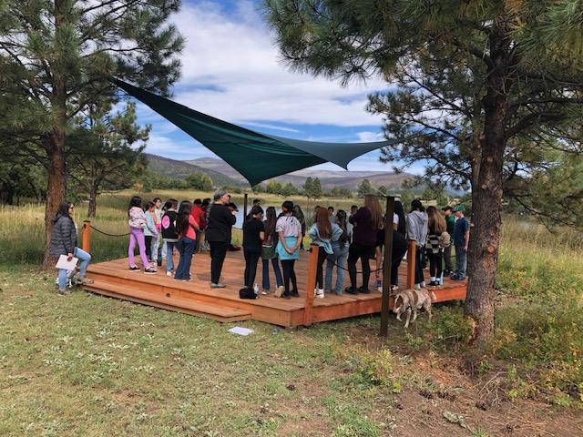 large group of kids standing outside on a wooden platform